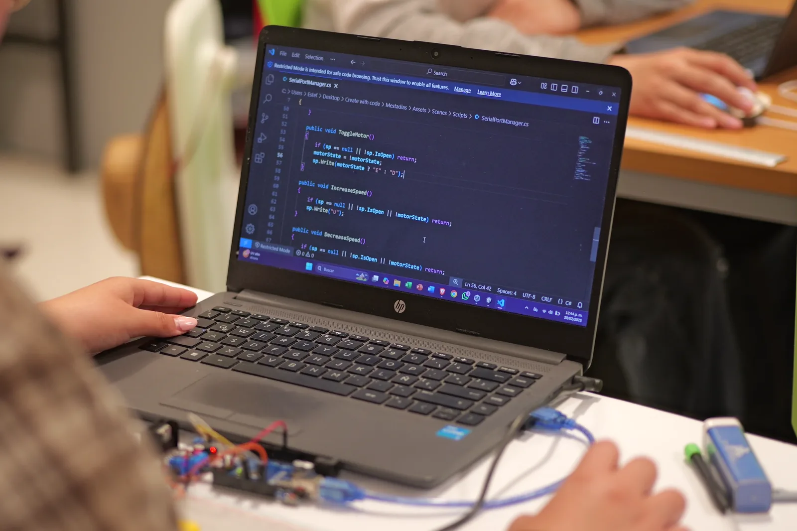 Workshop participant writing code on a laptop, with an electronics kit on the table.