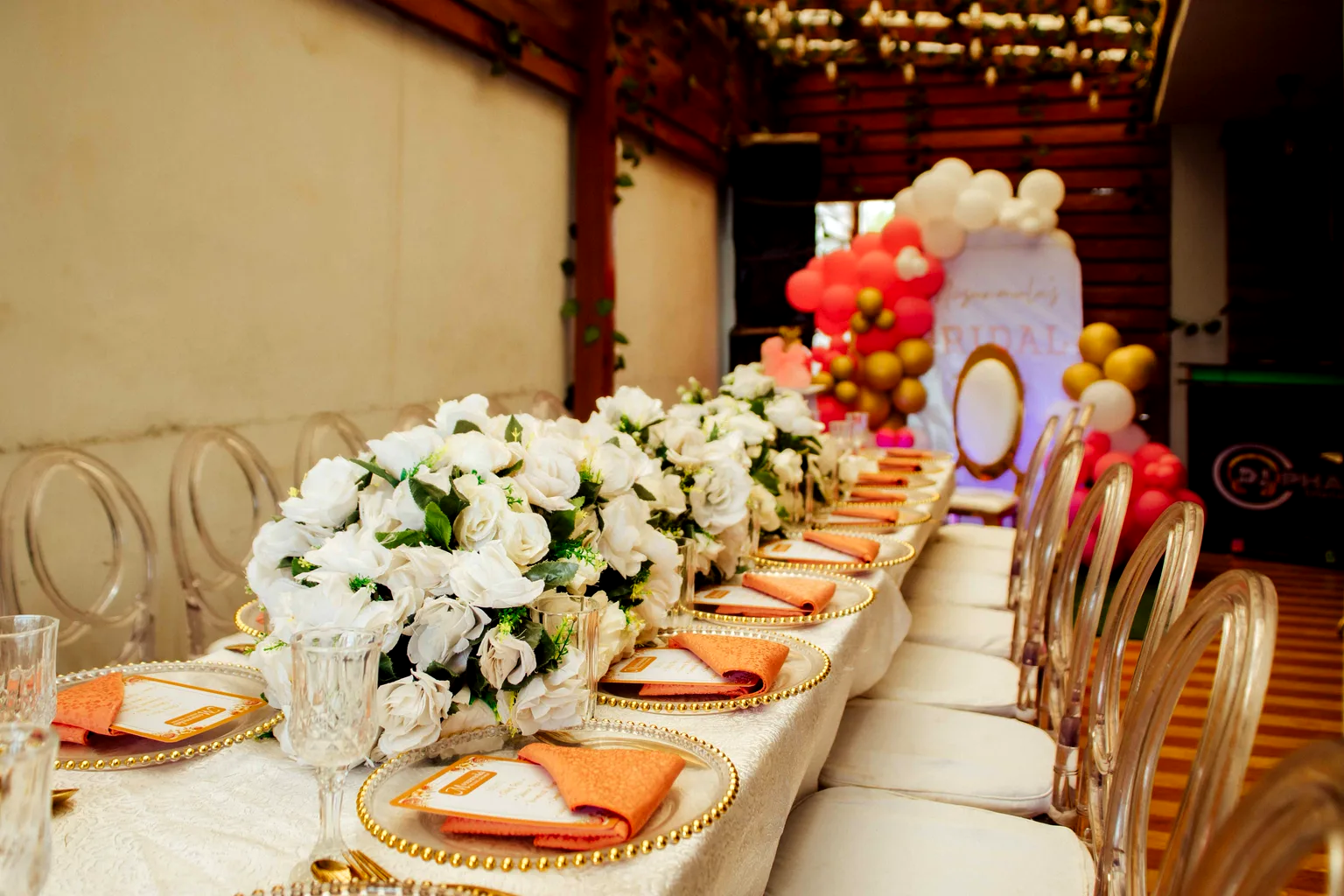 Mesa larga decorada para una celebración de empresa, con centros florales blancos y servilletas en tono terracota.