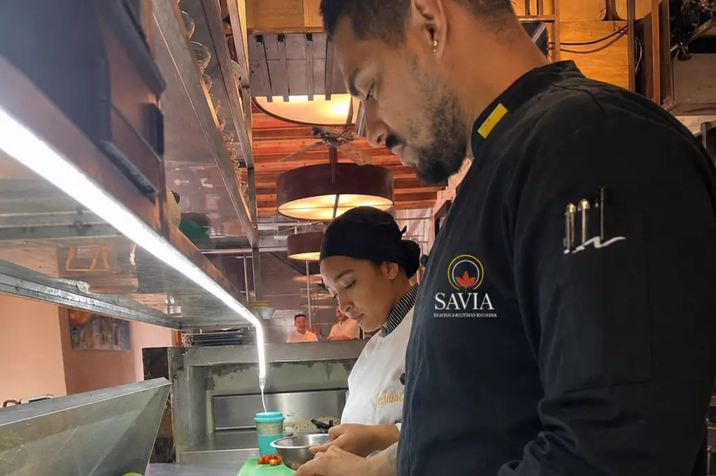 Andrés Jaraba, SAVIA's executive chef, checking the production line alongside a cook from the team, both in SAVIA uniform.