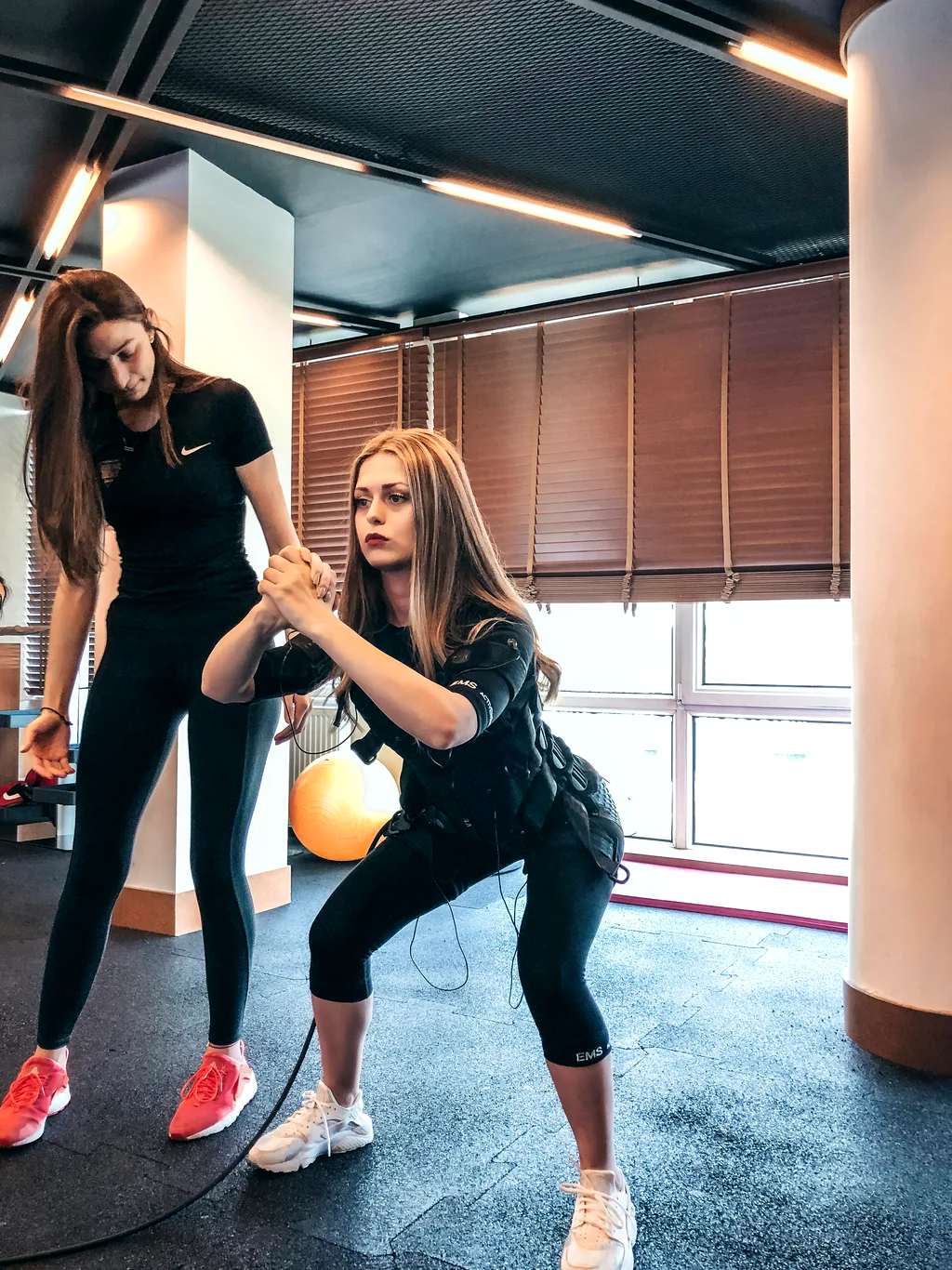 A trainer guiding a participant through a squat exercise.
