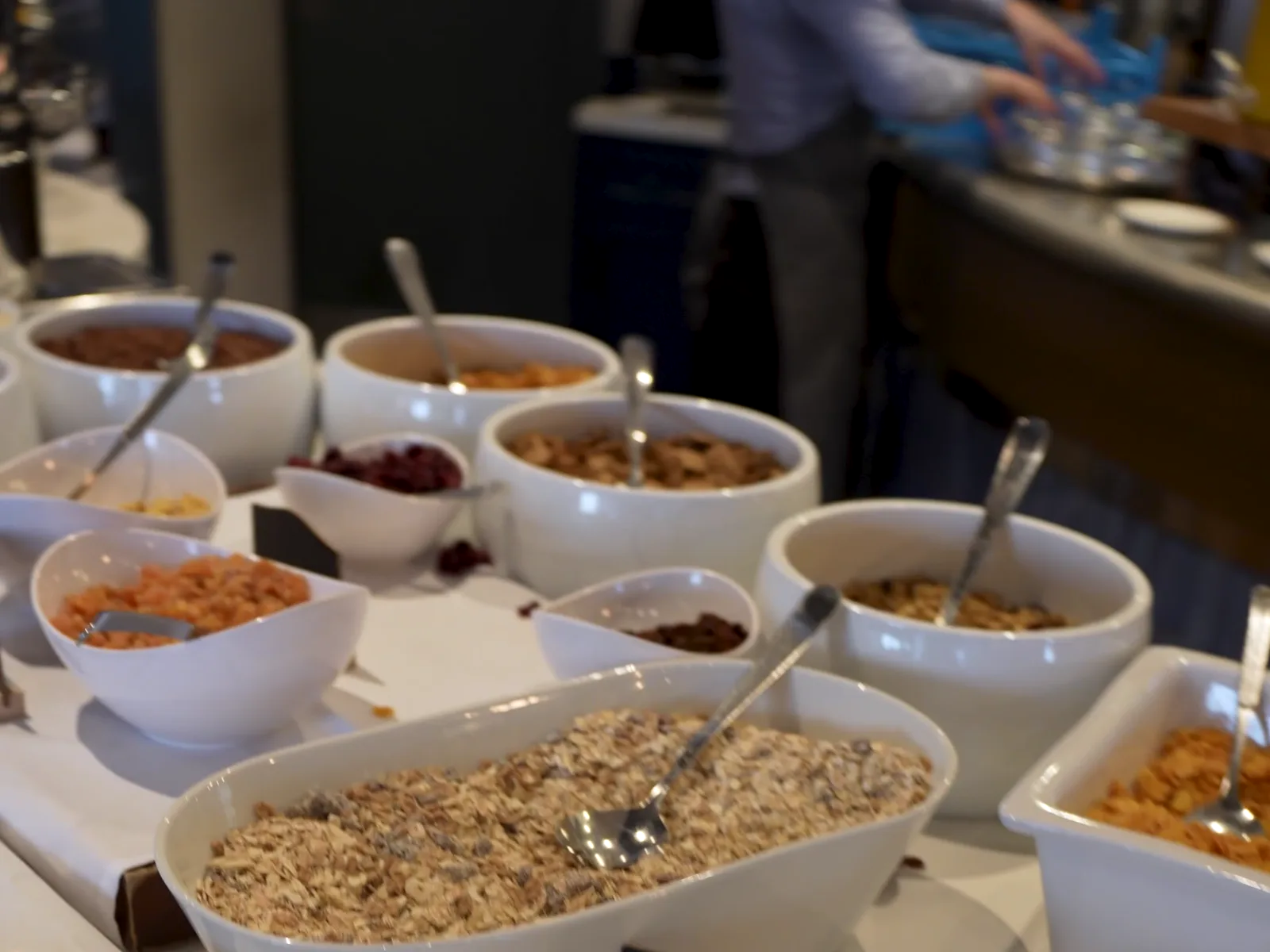 Estación de buffet montada con bowls rotulados y su personal atendiendo detrás del mostrador.