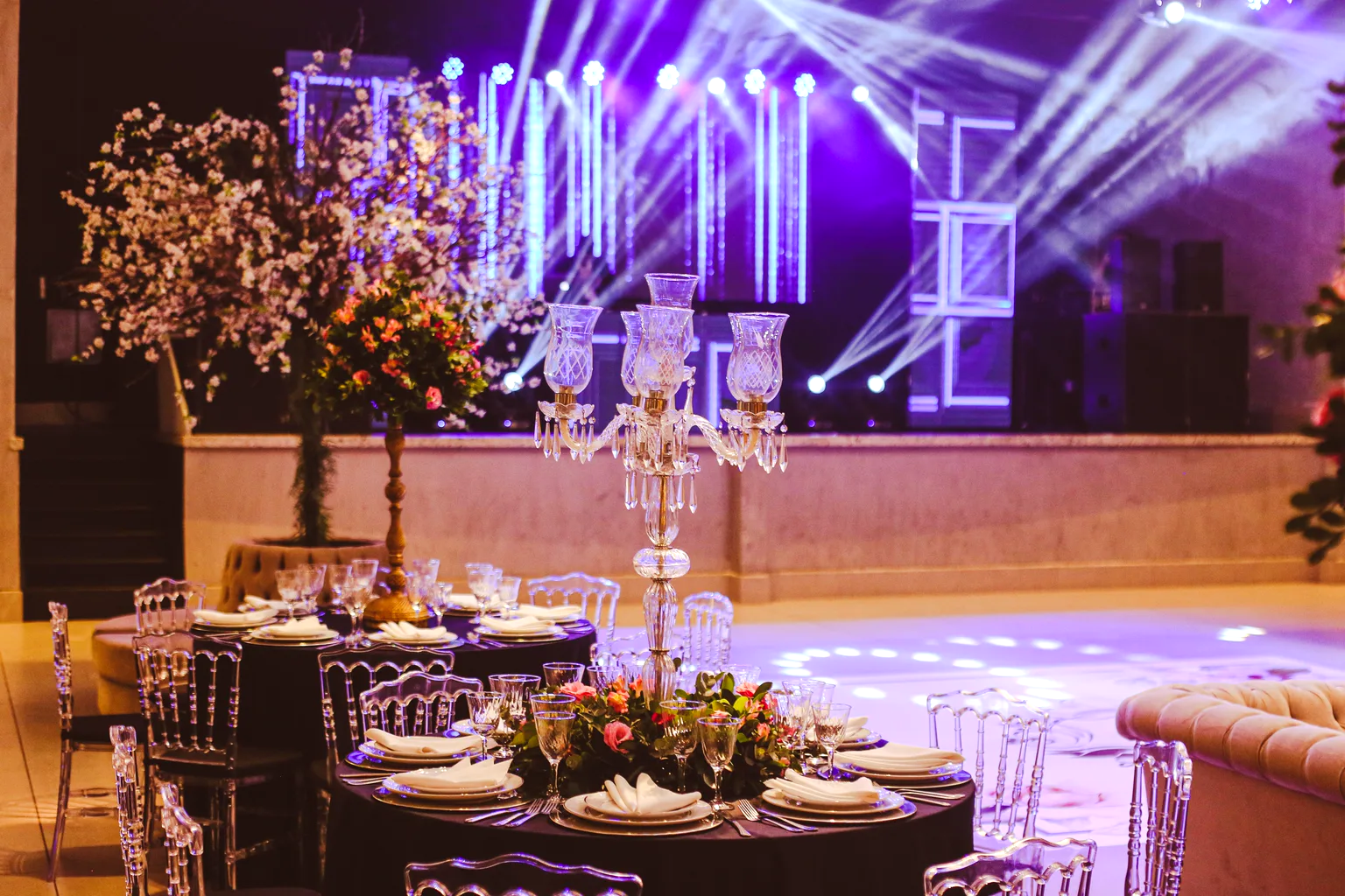 Montaje de evento a la medida con iluminación escénica, candelabros y mesas florales.