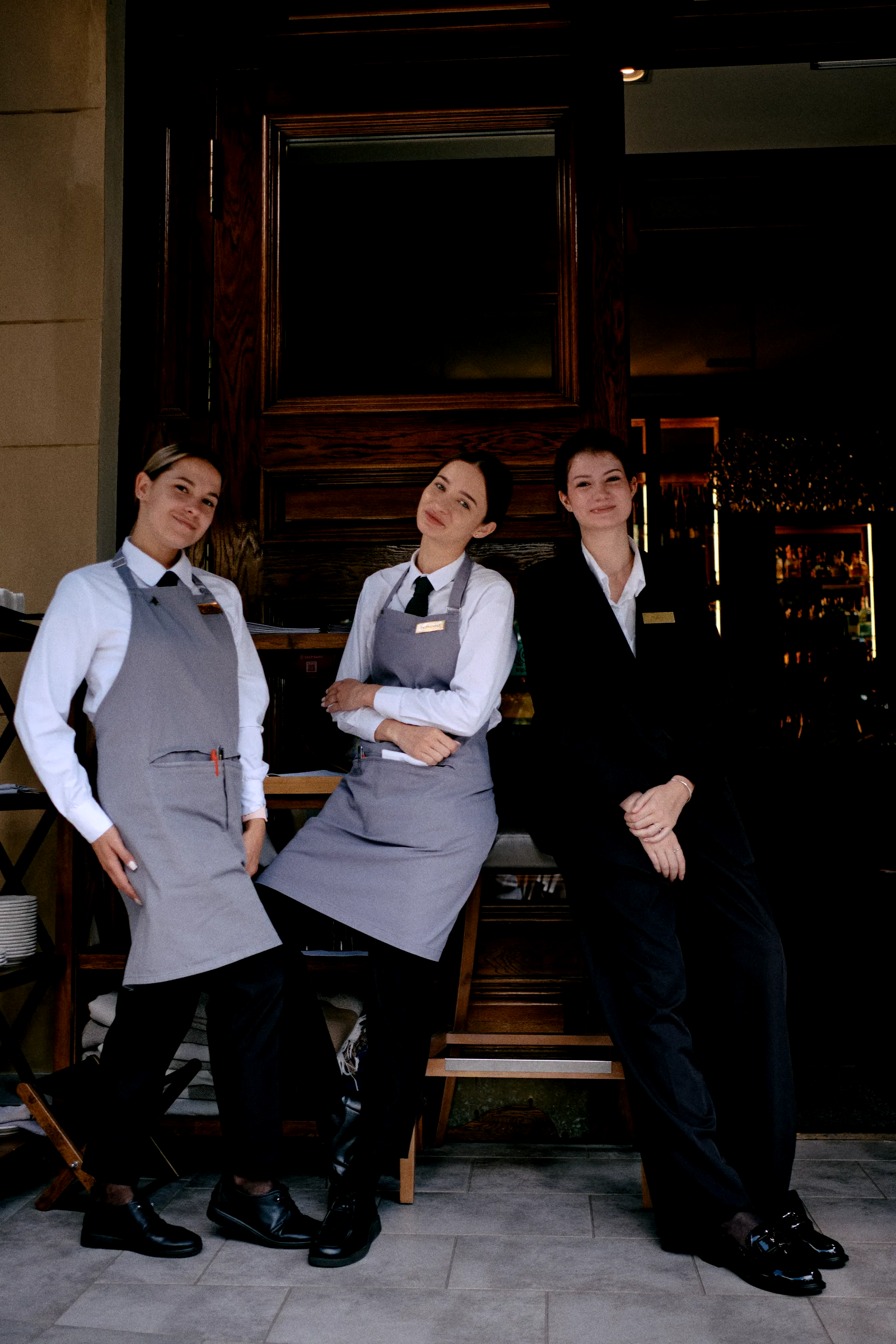 Tres integrantes del equipo de sala de un hotel, en uniforme y delantal, a la entrada del restaurante.