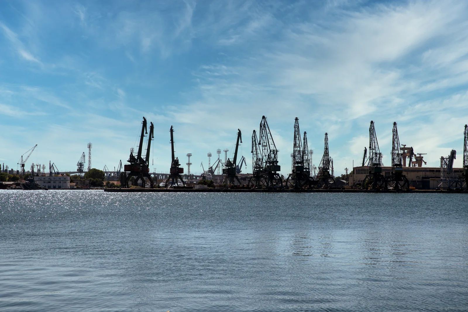 Grúas de muelle alineadas a lo largo de la terminal portuaria, vistas desde la bahía.