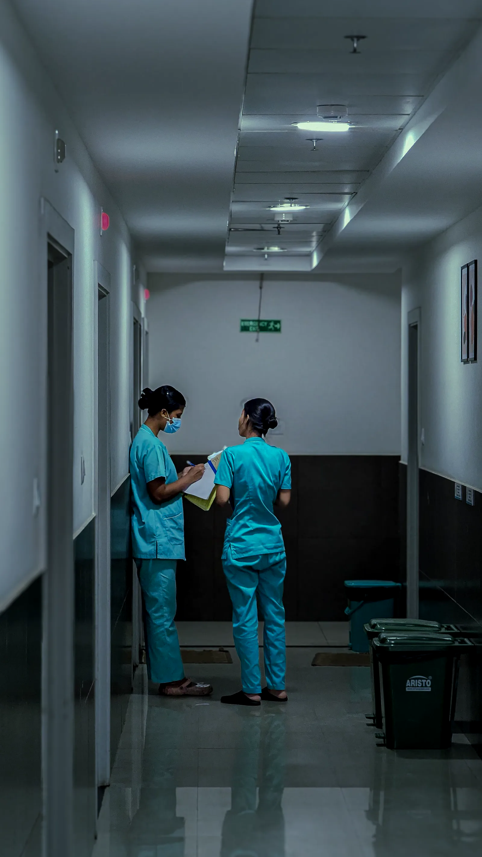 Dos profesionales de enfermería revisando la ronda en el pasillo de una institución de salud.