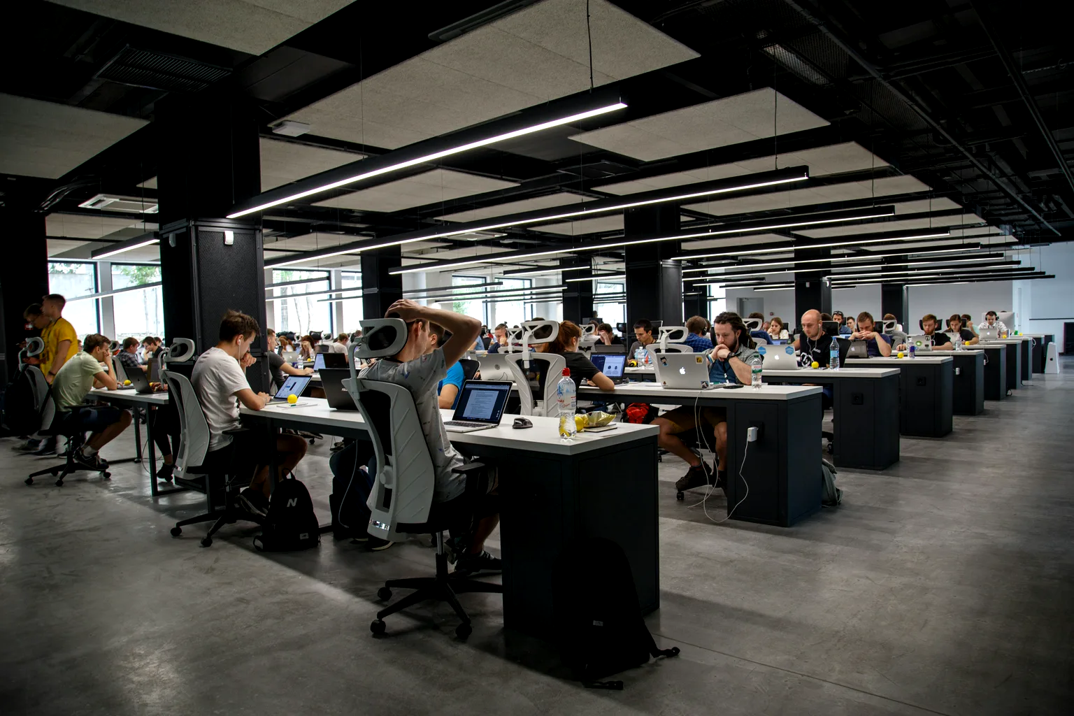 Oficina diáfana de planta abierta con decenas de puestos de trabajo ocupados.