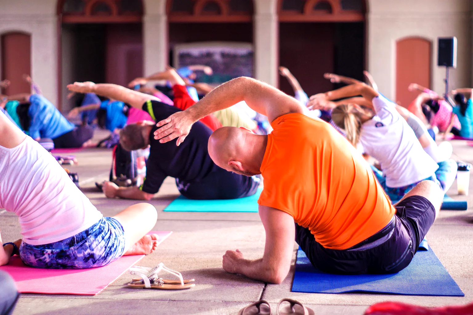 Sesión de yoga en grupo al aire libre, con los participantes en postura de estiramiento lateral sobre sus esterillas.